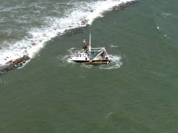 File A shrimp boat is grounded on South Galveston Jetty after three fisherman aboard were rescued by the Coast Guard. (U.S. Coast Guard photo by Air Station Houston)